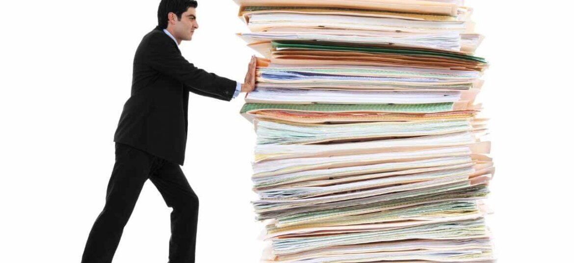 hombre empujando pila de papel